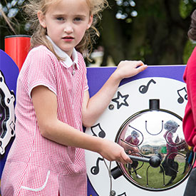 Girl playing with an outdoor musical drum play panel